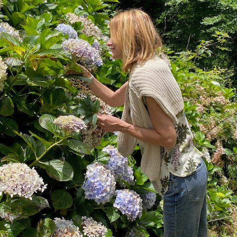 Wildfig designer Sam Drummond in a garden surrounded by hydrangeas