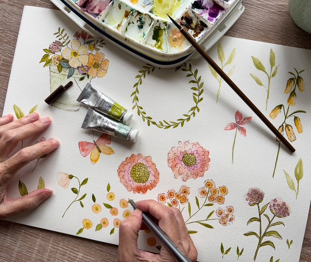 Artistic creation of floral designs on paper with watercolor paints and brushes.