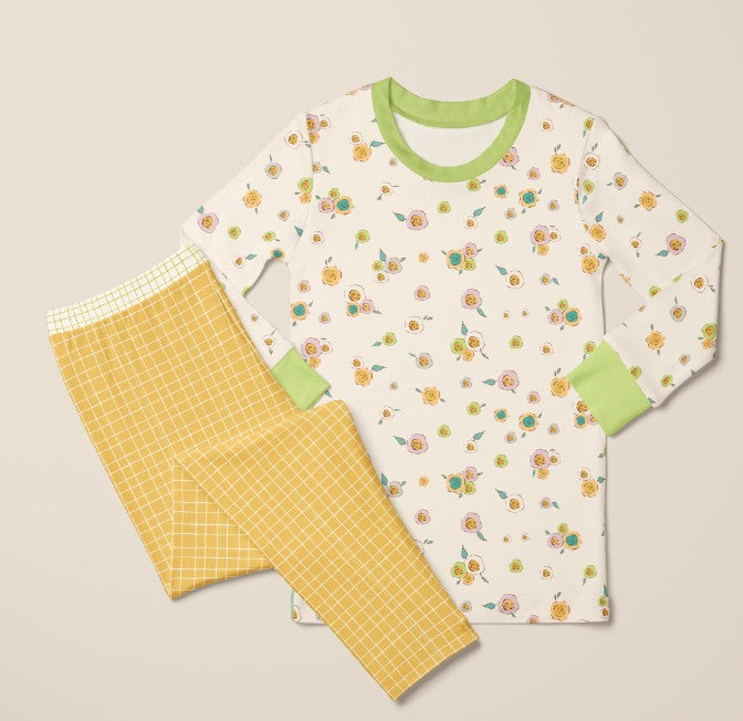 Children's pajama set with floral top and yellow pants on a beige background